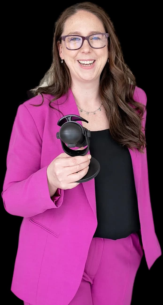 Claire Lockey, host of The Business of You Podcast, in a magenta suit holding a microphone